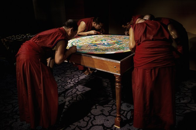 The monks putting the finishing touches on the nearly completed mandala.